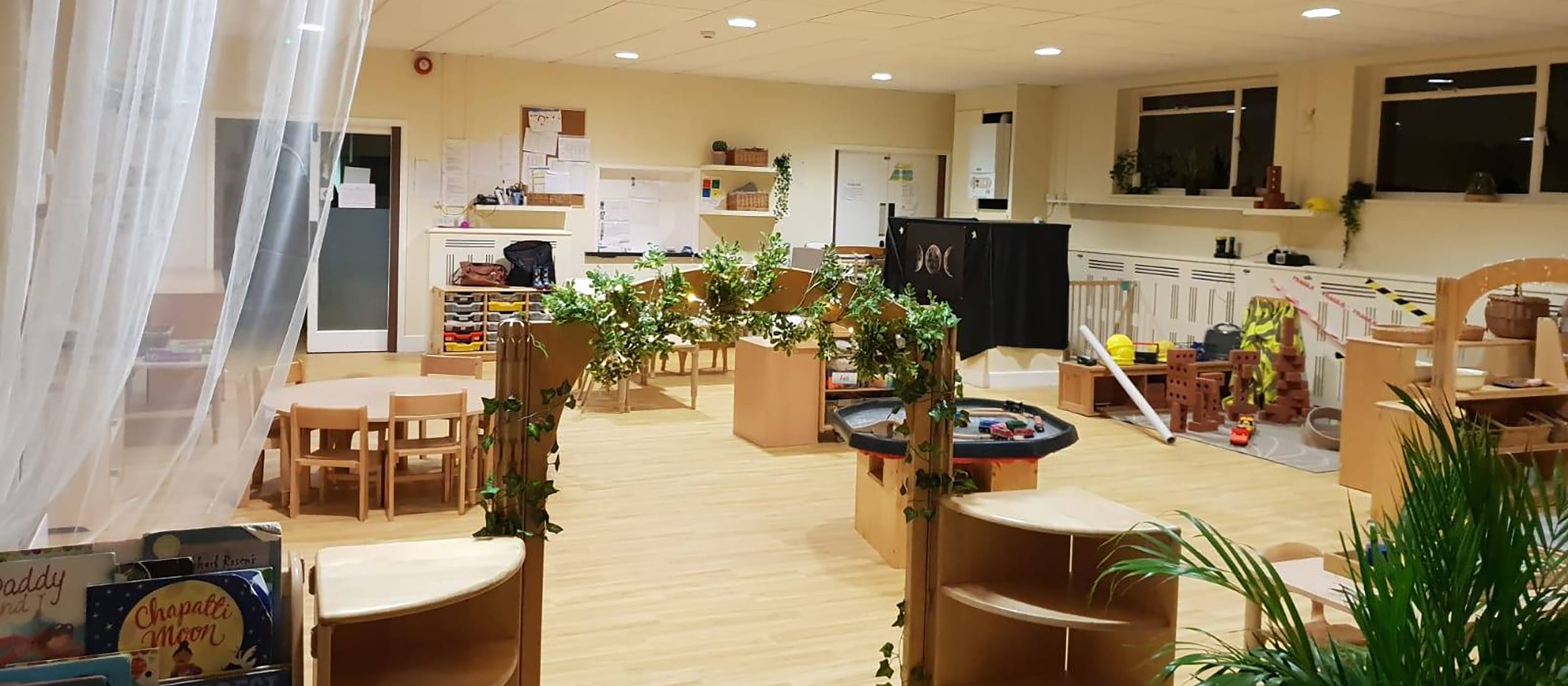 A small outdoor play area with artificial turf, wooden benches, and mushroom stools
