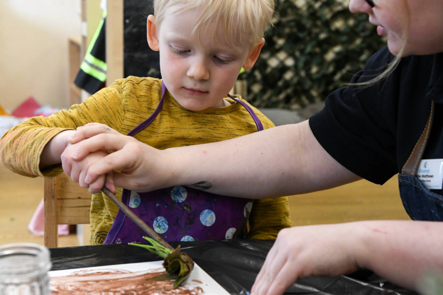 A boy paints using natural materials