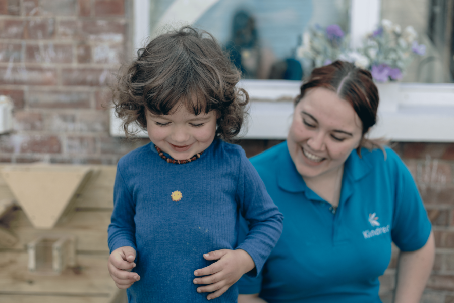 Adult and child smiling outdoors.