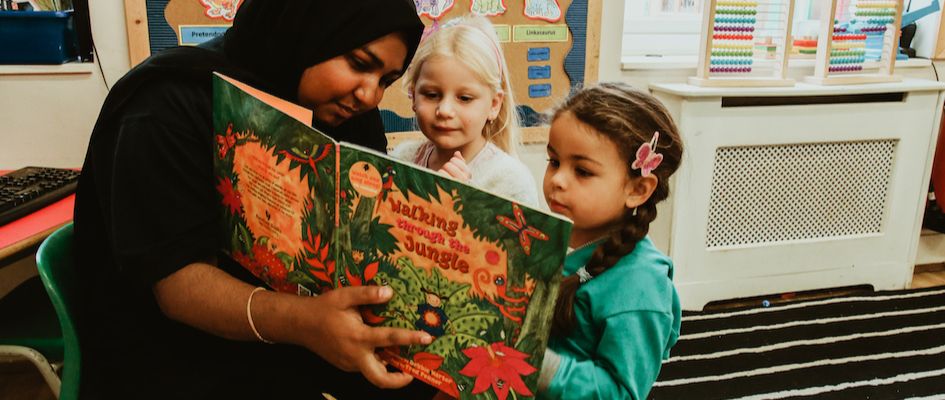 A practitioner reads a story to two children