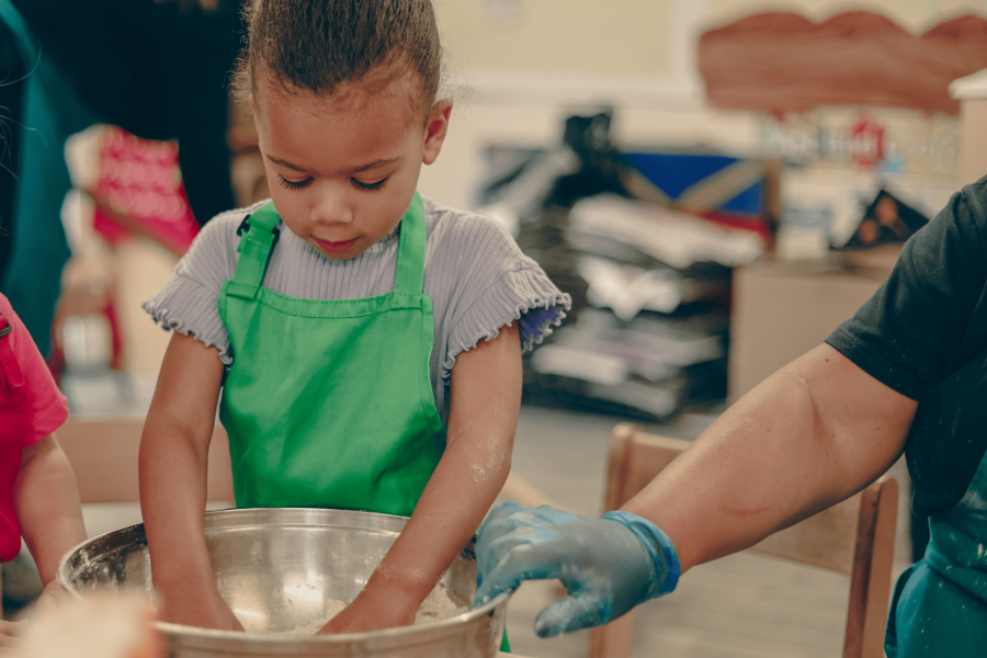 a girl is knreading flour in a bowl