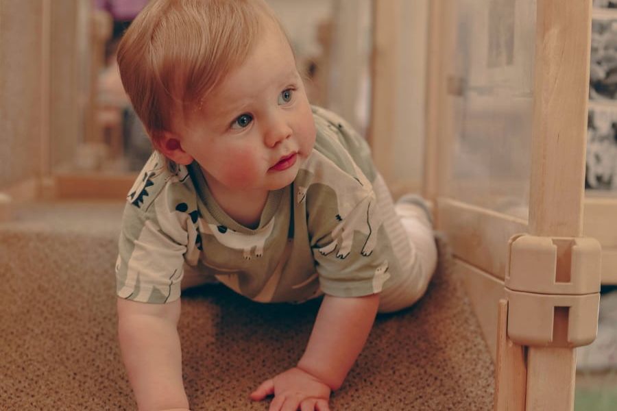 A baby is crawling down a wooden indoor climbing frame