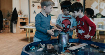 A group of children gathered and playing around a water table activity