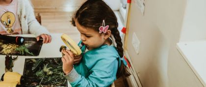 A girl uses a magnifying glass to inspect an insect
